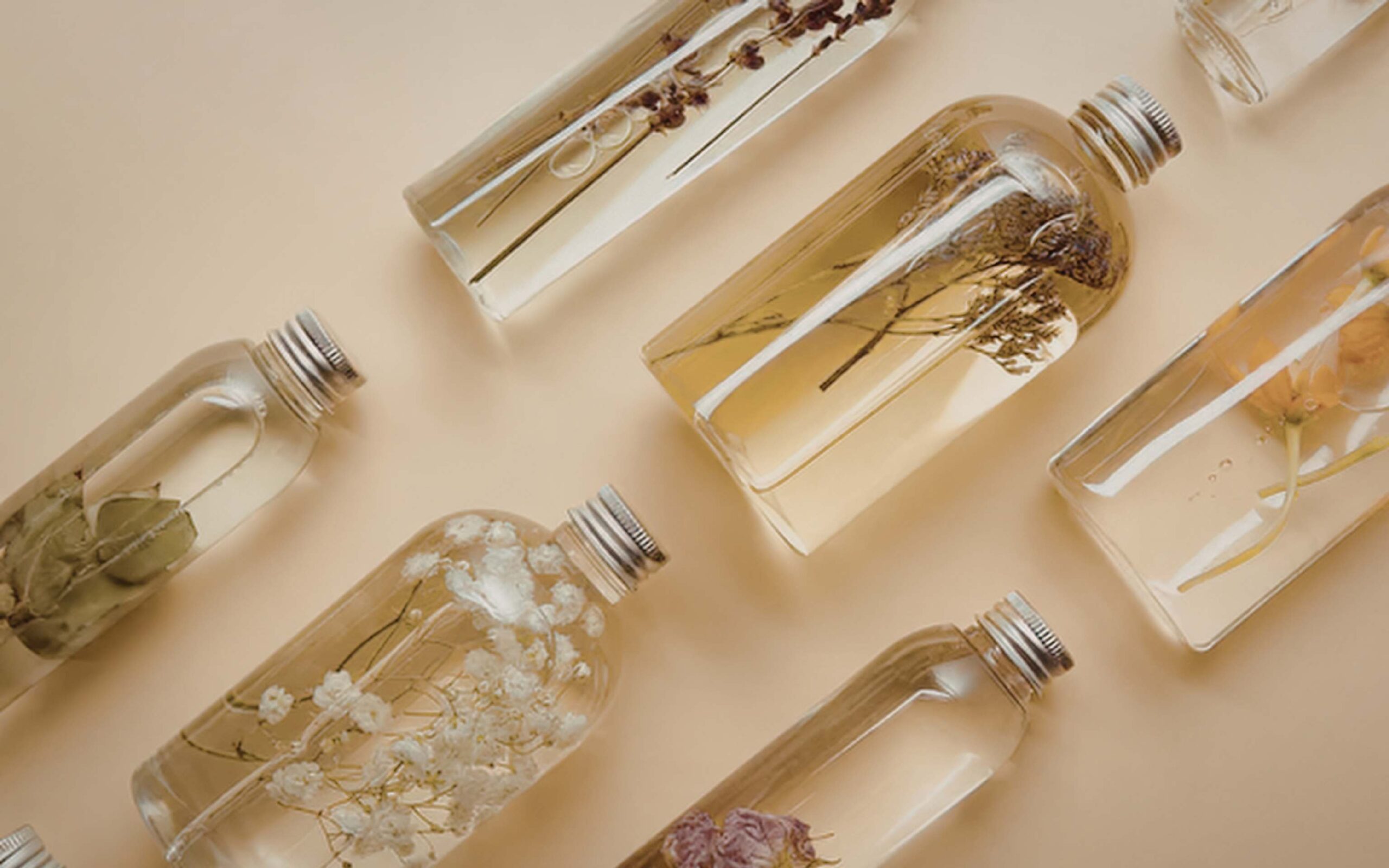 Jojoba and rosehip oil bottles alongside green tea leaves on a natural wood surface